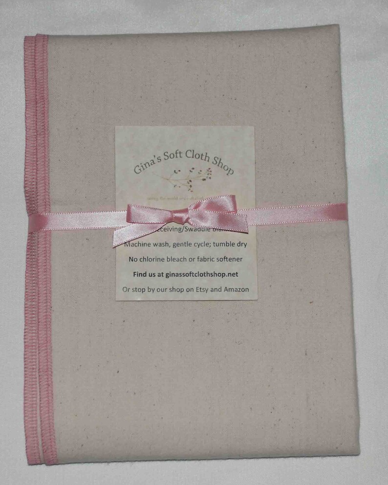 May include: A beige cloth square with pink edging, tied with a pink ribbon. The cloth is packaged with a white card that reads "Gina's Soft Cloth Shop" and includes care instructions and contact information.