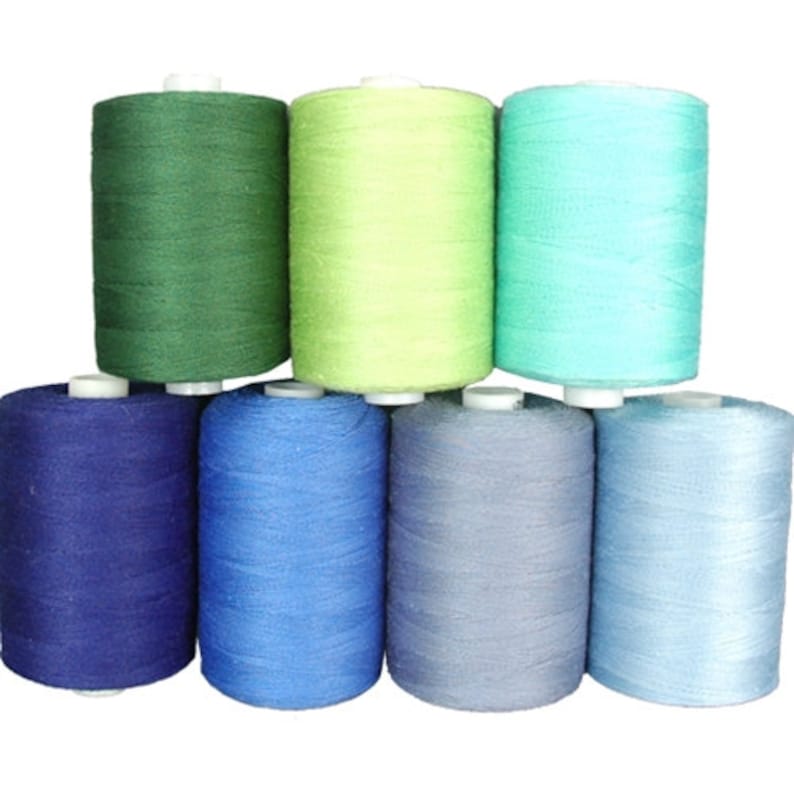 Puede incluir: Ocho carretes de hilo en varios colores, incluyendo verde, azul y azul claro. Los carretes est&aacute;n dispuestos en forma de pir&aacute;mide.