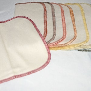 May include: A set of 10 reusable cotton makeup remover pads with different colored stitching. The pads are folded in half and arranged in a rainbow pattern.
