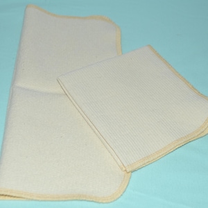 May include: Two white cotton cloths with a light yellow border. The cloths are folded and have a textured surface.