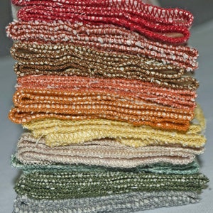 May include: A stack of eight colorful dishcloths, folded neatly. The cloths are made of a soft, textured fabric and feature a variety of colors, including red, orange, yellow, green, and gray.