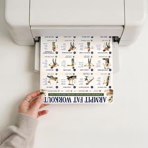 Op de afbeelding: Een geprint vel dat uit een witte printer komt met een raster van zestien genummerde oefenillustraties getiteld ARMPIT FAT WORKOUT. Elk vierkant toont een persoon die een specifieke oefening voor het bovenlichaam uitvoert.