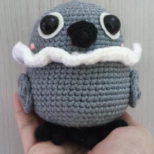 sylus grumpy crow amigurumi from Love and Deepspace, shown from the front with big black eyes, black beak, and a white ruffled collar.