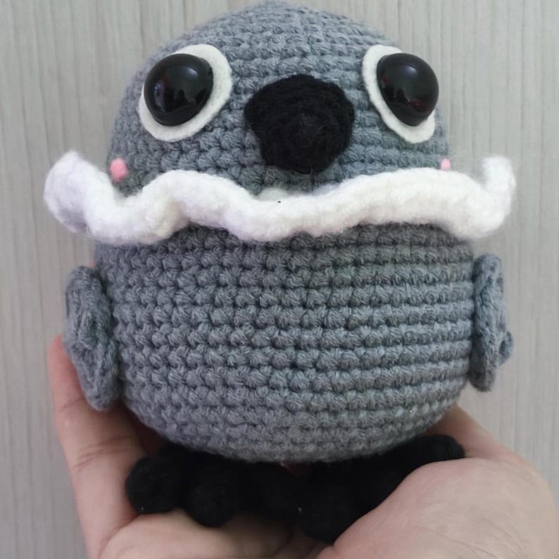 sylus grumpy crow amigurumi from Love and Deepspace, shown from the front with big black eyes, black beak, and a white ruffled collar.
