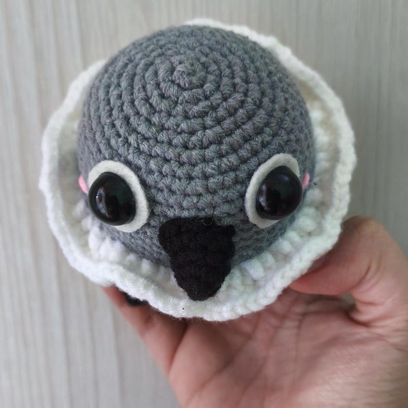 top-down view of sylus grumpy crow amigurumi, focusing on eye placement, black beak, and ruffled collar shape.