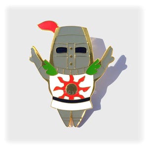 May include: Gold-colored enamel pin of a knight in white armor with a red sun on their chest. The knight is holding their arms up in a triumphant pose.