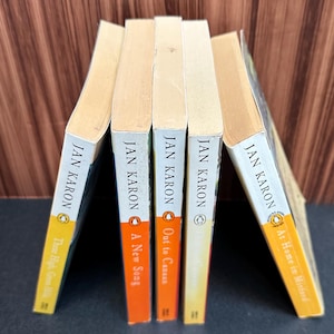 May include: A stack of five paperback books by author Jan Karon. The books are titled "These High, Green Hills", "A New Song", "Out to Canaan", "The Home Place", and "At Home in Mitford".