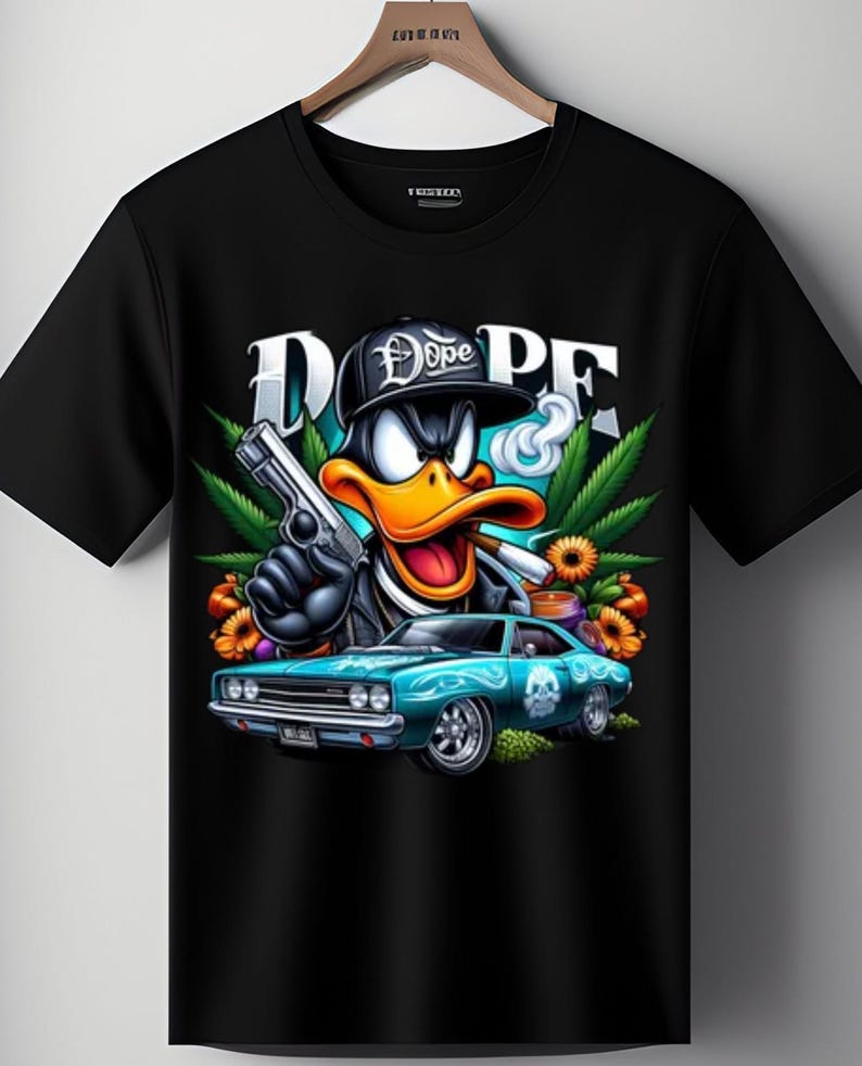 May include: Black t-shirt with a cartoon duck wearing a cap that says "Dope" and holding a gun and a lit cigarette. The graphic includes a teal car, cannabis leaves, and the word "DOPE" in large letters.
