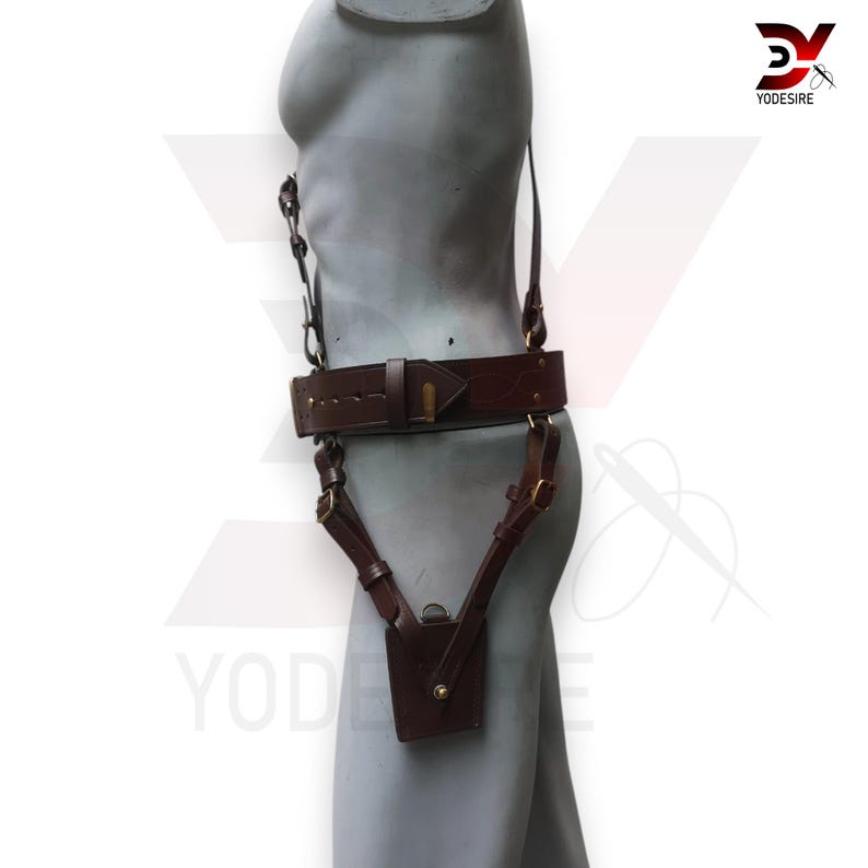 Pu&ograve; includere: Una cintura in pelle marrone con una fondina attaccata. La fondina &egrave; anch'essa in pelle marrone e ha una fibbia in ottone. La cintura &egrave; indossata da un manichino.