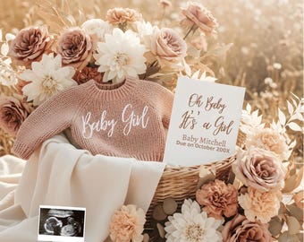 May include: A pink knitted sweater with "Baby Girl" embroidered on the front rests in a wicker basket, surrounded by roses and dahlias. A card reads "Oh Baby It's a Girl" with an ultrasound image. A beautiful announcement.