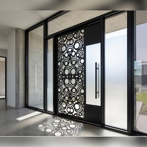 Peut inclure: Une porte noire moderne avec un motif circulaire décoratif, encadrée de grands panneaux de verre. La porte comporte une longue poignée verticale et s'inscrit dans un design architectural contemporain avec des éléments en béton et en verre.