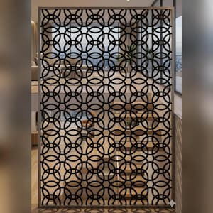 Peut inclure: Une cloison décorative en métal noir avec un motif répétitif de cercles imbriqués. La cloison est encadrée dans un métal de couleur claire et est positionnée devant un escalier, ajoutant un élément architectural moderne à l'espace.