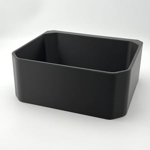 May include: A matte black rectangular storage container with rounded corners and a slightly tapered design. The container is empty and sits on a white surface, showcasing its simple, modern aesthetic. The container is likely used for organizing items.