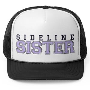 Puede incluir: Gorra de camionero negra y blanca con un panel frontal blanco y una malla negra en la parte posterior. El panel frontal presenta el texto "SIDELINE SISTER" en letras negras y moradas.