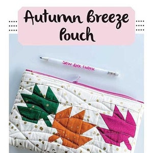 May include: A quilted pouch with a zipper closure featuring a design of three autumn leaves in shades of green, orange, and pink on a white background with gold polka dots. The pouch is 6 inches by 10 inches and is described as "Charm & Scrap Friendly".