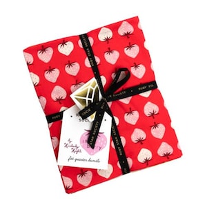 May include: A red fat quarter bundle featuring a strawberry pattern. The fabric is tied with a black ribbon that reads "RUBY STAR SOCIETY." A tag with a gold geometric design and the text "by Kimberly Knight" is attached.