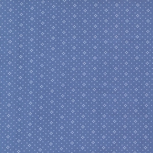 May include: A close-up of a blue fabric with a repeating pattern of small white floral shapes. The fabric has a slightly textured appearance, and the white shapes are evenly spaced across the surface.