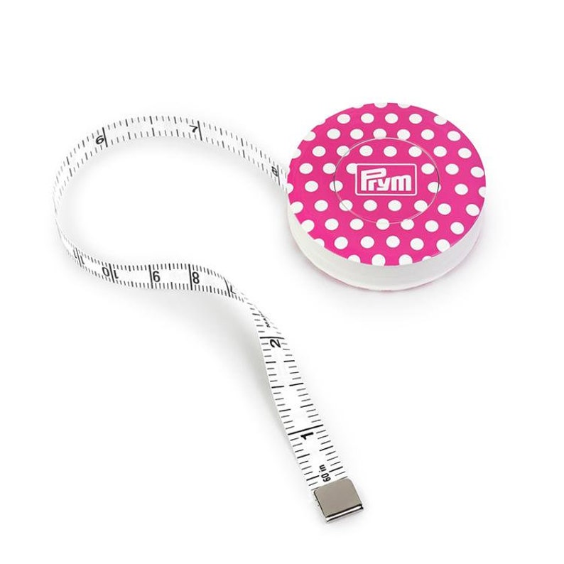 May include: A pink and white polka dot measuring tape with a white tape measure that extends 60 inches. The tape measure has a metal end and the case has the word "Prym" printed on it.