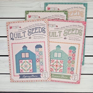 May include: Several quilt pattern books titled "Quilt Seeds" are displayed. The covers feature barn illustrations in blue and teal, with the text "Spring Barn" and "Summer Barn". The books are by Lori Holt of Bee in my Bonnet.