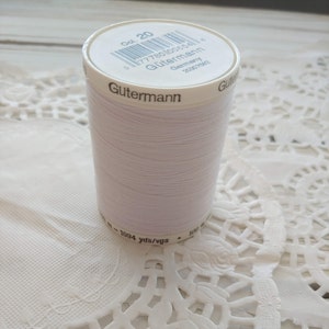 May include: A white spool of Gütermann thread with a label that reads "Col. 20", "177780800654", "Gütermann", "Germany", and "20307882". The spool is labeled with "1094 yds/vgs" and "100 m".