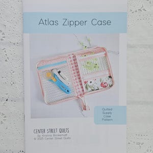 May include: A brochure titled "Atlas Zipper Case" featuring a pink quilted supply case with a zipper, pockets, and a rotary cutter. The brochure is from Center Street Quilts, © 2025.