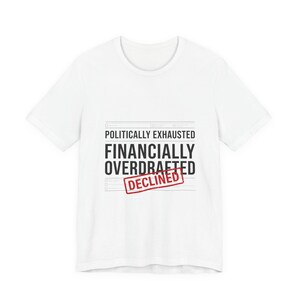 Könnte beinhalten: Weißes T-Shirt mit den schwarzen Aufschriften "POLITISCH ERSCHÖPFT" und "FINANZIELL ÜBERZOGEN", mit einem roten Stempel "ABGELEHNT". Ein Kleidungsstück für den Alltag.