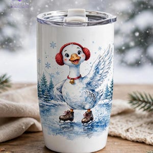 Puede incluir: Un vaso cil&iacute;ndrico blanco con tapa transparente que presenta una ilustraci&oacute;n en acuarela de un ganso con orejeras rojas y un collar con cascabel, patinando sobre hielo en un estanque rodeado de pinos y copos de nieve.