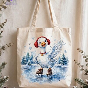 Puede incluir: Una bolsa de tela beige con una ilustraci&oacute;n en acuarela de un ganso blanco que lleva orejeras rojas y un collar con una peque&ntilde;a campana. El ganso patina sobre un estanque helado rodeado de pinos azules y copos de nieve.