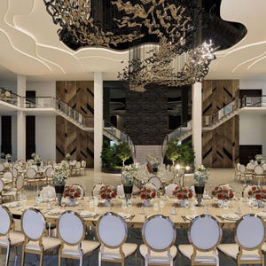 May include: A large, white, rectangular room with a high ceiling and a large, black chandelier. The room is decorated with white chairs and tables, and there are flowers on the tables. The room is set up for a wedding reception.