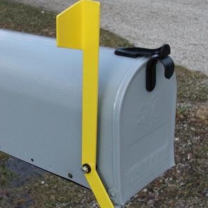 May include: A gray mailbox with a yellow flag attached to the side. The flag is bent at a 90-degree angle and has a black metal bracket.