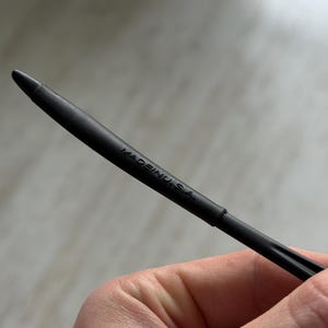 K&ouml;nnte beinhalten: Eine schwarze Stiftmine mit einer Spitze. Der Text "MADE IN U.S.A." ist auf dem Stift aufgedruckt. Der Stift wird von einer Person gehalten.