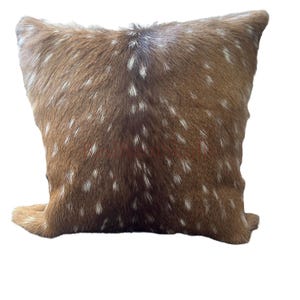 May include: A square throw pillow covered in brown animal hide with a natural pattern of white spots. The texture of the fur is visible across the entire surface, featuring a darker brown central stripe that runs vertically down the middle.