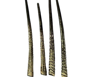 May include: Four shofar horns, traditional Jewish ceremonial instruments, made from ram's horns. The horns are brown and black with a natural, textured finish.