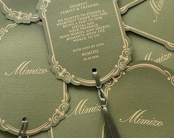 May include: Olive green gift tags with gold decorative borders and tassels. The tags have the word "Mimizo" printed on them, along with a message that reads "Dearest Family & Friends, We wanted to extend a heartfelt thank you..."