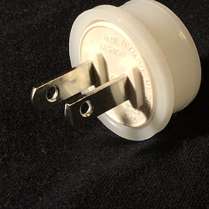 May include: White plastic electrical adapter with two prongs. The adapter has the text "MADE IN CHINA FASHION 15-15" printed on it.