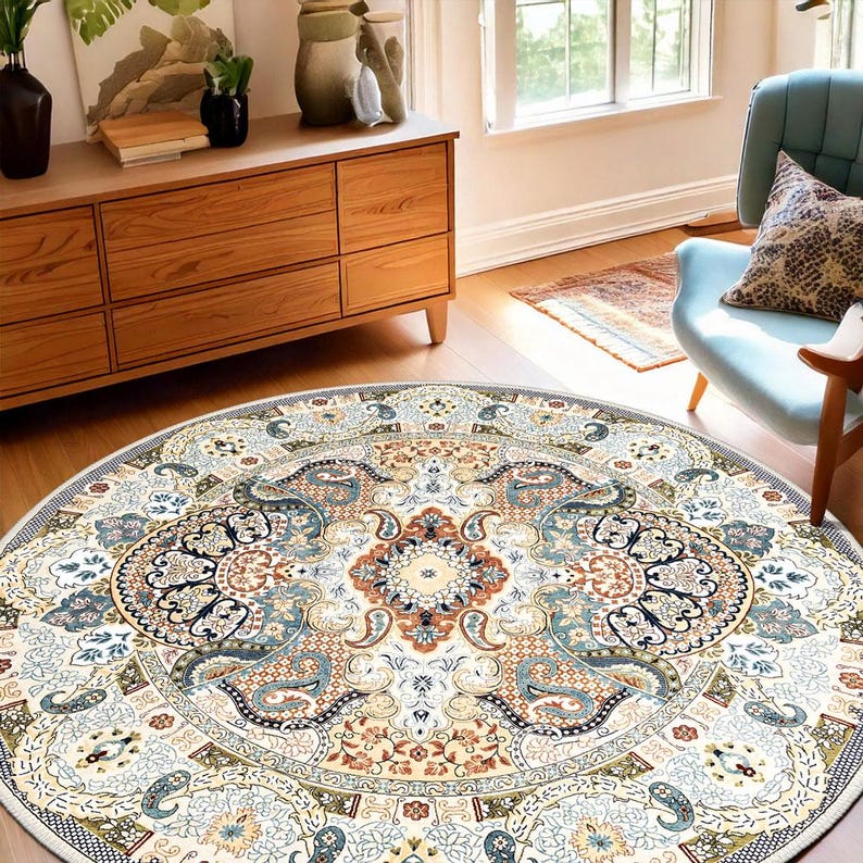 Puede incluir: Una alfombra redonda con un dise&ntilde;o intrincado y ornamentado. La alfombra presenta un medall&oacute;n central en tonos beige, azul y &oacute;xido, rodeado por un borde detallado. El patr&oacute;n general recuerda a las alfombras persas tradicionales.