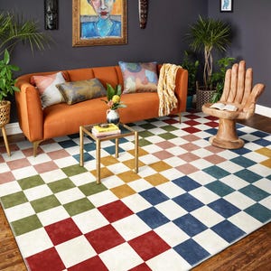 Puede incluir: Una colorida alfombra a cuadros en un salón. La alfombra presenta un patrón de cuadrados en varios colores, incluyendo rojo, azul, verde y blanco. Un sofá naranja, una silla de mano de madera y una pequeña mesa dorada también son visibles.