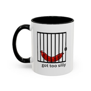 May include: White ceramic mug with a black handle and interior. The mug features a cartoon illustration of a red sausage behind black bars with a padlock, and the text "got too silly" in black.
