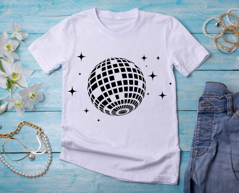May include: White t-shirt with a black disco ball graphic and small stars printed on the front.