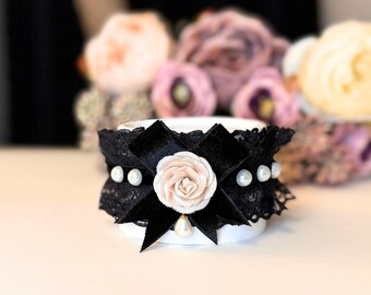 May include: A black lace bracelet with a white satin bow and pearl accents. The bow is centered on the bracelet and has a single pearl in the center.