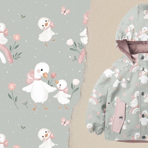 Könnte beinhalten: Kinderjacke mit Entenmuster. Die Jacke ist hellgrün mit einem sich wiederholenden Muster aus weißen Enten, rosa Schleifen, Regenbogen und Schmetterlingen. Die Jacke hat eine Kapuze und rosa Akzente.