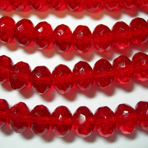 May include: A strand of red faceted glass beads. The beads are round and have a shiny finish.