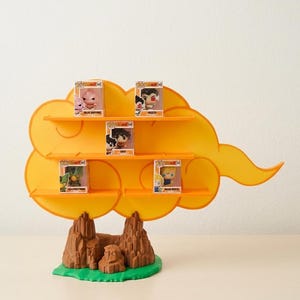 Puede incluir: Una estantería de exhibición amarilla en forma de nube con múltiples niveles, que contiene varias pequeñas figuras de personajes en cajas. La base es marrón y verde, parecida a un paisaje rocoso. La estantería está diseñada para guardar objetos de colección.