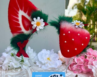 May include: A pair of strawberry-themed faux fur ears on a clear headband. The red ears are detailed with white seeds and a green trim, and adorned with white daisy accents and small red bows. The image also includes a business card that says "Animal faux fur ears" and "E. BinggiShop".