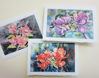 May include: Three watercolour paintings of bougainvillea flowers. The first painting features pink flowers with dark green leaves against a dark background. The second painting features purple flowers with green leaves against a light blue background. The third painting features red flowers with green leaves against a dark blue background.
