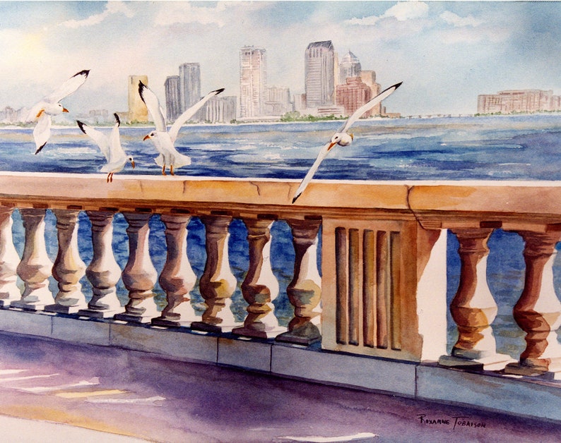 Peut inclure: Une peinture &agrave; l'aquarelle d'une ville avec un pont et des mouettes. Le pont a une balustrade en pierre avec une s&eacute;rie de colonnes. Les mouettes sont blanches et volent au-dessus de l'eau. La ville est en arri&egrave;re-plan et est compos&eacute;e de b&acirc;timents hauts. La peinture est sign&eacute;e par l'artiste, Suzanne Torrison.