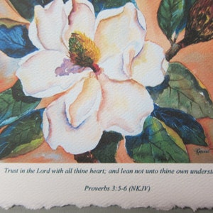 Peut inclure: Une peinture &agrave; l'aquarelle d'une fleur de magnolia blanche avec des feuilles vertes et un bourgeon brun. La peinture contient une citation de Proverbes 3:5-6 (NKJV) qui dit : "Fais confiance &agrave; l'&Eacute;ternel de tout ton c&oelig;ur, et ne t'appuie pas sur ta propre intelligence."