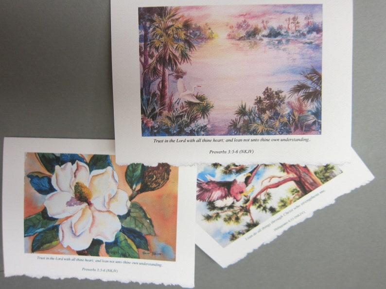Peut inclure: Trois aquarelles avec des citations inspirantes. La premi&egrave;re peinture repr&eacute;sente une fleur de magnolia blanche avec des feuilles vertes sur un fond p&ecirc;che. La deuxi&egrave;me peinture montre un h&eacute;ron blanc debout dans un marais avec des palmiers et un coucher de soleil en arri&egrave;re-plan. La troisi&egrave;me peinture montre un oiseau rouge perch&eacute; sur une branche avec des feuilles vertes et un ciel bleu en arri&egrave;re-plan. Les trois peintures incluent la citation "Fais confiance &agrave; l'&Eacute;ternel de tout ton c&oelig;ur, et ne t'appuie pas sur ta propre intelligence. Proverbes 3:5-6 (NKJV)"