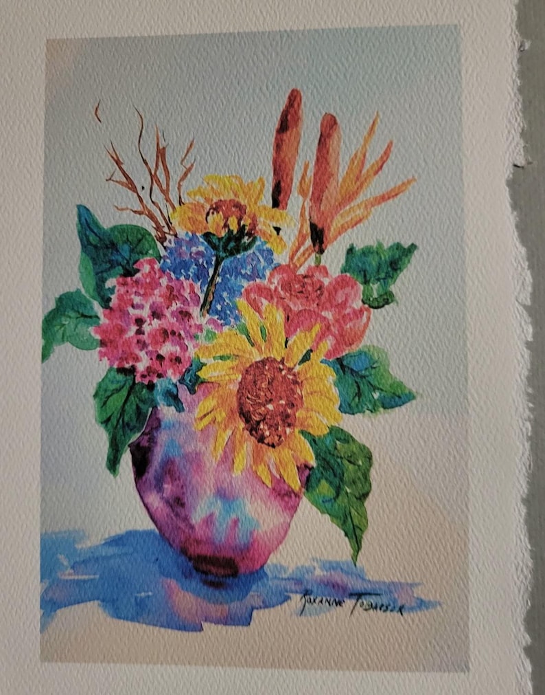 May include: A watercolor painting of a bouquet of flowers in a pink vase. The flowers include sunflowers, hydrangeas, and other blooms in shades of yellow, red, blue, and orange. The vase is sitting on a blue surface.