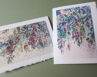 May include: Two watercolour paintings of wisteria flowers. The first painting shows a close-up of the flowers, while the second painting shows a wider view of the flowers hanging from a branch.